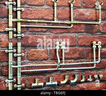 Metallo tubi idraulici su un muro di mattoni Foto Stock