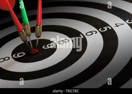 Immagine ravvicinata di colore rosso e verde dart frecce sul centro di dartboard, metafora per target di successo e vincitore del concetto. Foto Stock