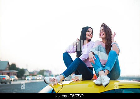 Migliore Femmina amici tifo in auto road trip al tramonto. Le persone felici outdoor in vacanza tour. Il concetto di amicizia a viaggiare con nostalgico positivo Foto Stock