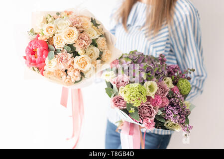 Due bellissimi mazzi di fiori misti in womans mani. Il lavoro del fioraio presso un negozio di fiori. Delicati colori pastello. Fresh cut flower. Foto Stock