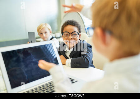 I bambini come la gente di affari con computer portatili come innovazione nella riunione di affari Foto Stock