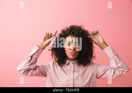 Immagine del triste bella giovane donna africana in posa isolate su rosa sfondo parete vestito in pigiama. Foto Stock