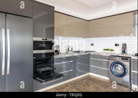 Spaziosa e lussuosa ben progettato e moderno di colore grigio, beige e bianco cucina con piastrelle in marmo Pavimento. Alcuni gavoni e porta del forno elettrico sono aperti Foto Stock