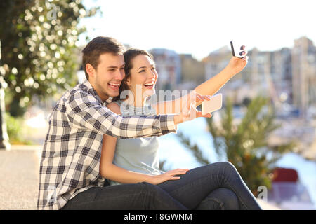 Coppia felice tenendo selfies con i loro telefoni intelligenti su vacanze estive Foto Stock