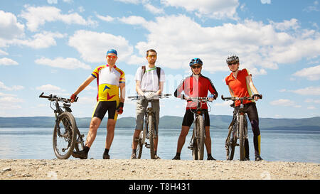 Un gruppo di ciclisti sulla riva di un lago di montagna. l uomo all'esterno. mountain bike Foto Stock