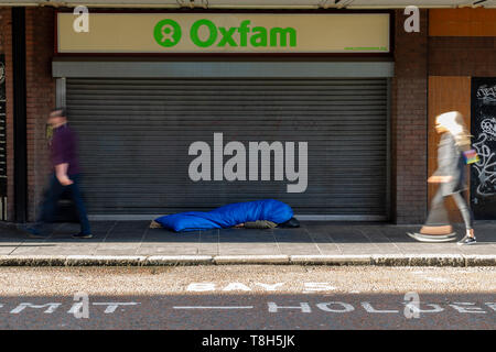 Belfast 13 maggio 2019. Un uomo dorme grezzo su Castle Street, Belfast, mentre i membri del pubblico a piedi passato. Foto Stock