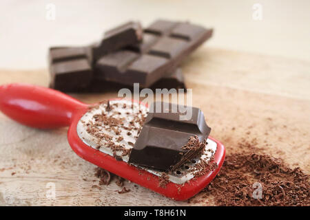 Cioccolato, grattugia e cioccolato grattugiato su di un tagliere Foto Stock