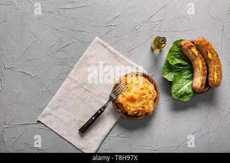 Piastre con gustoso stufato di cavolo e salsicce alla griglia sulla tabella grigia Foto Stock