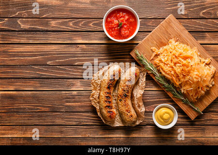 Gustoso stufato di cavolo con salsicce alla griglia e salse sul tavolo di legno Foto Stock