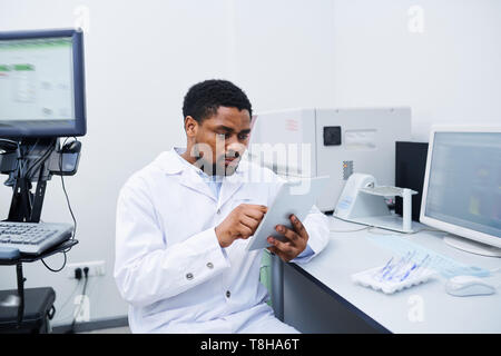 Nero scienziato medico analizzando i dati sui tablet Foto Stock