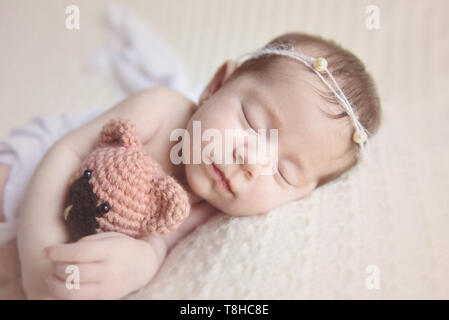 Ragazza neonata slepping tenendo un orsacchiotto Foto Stock