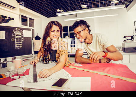 Designer di moda di prendere tutte le misure e sorridente. Foto Stock