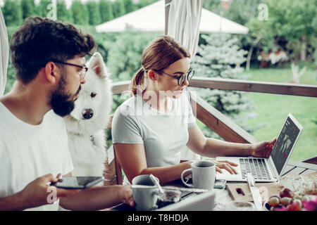 Analista di bella mostra grafico al marito mentre si lavora in modalità remota all'esterno. Foto Stock