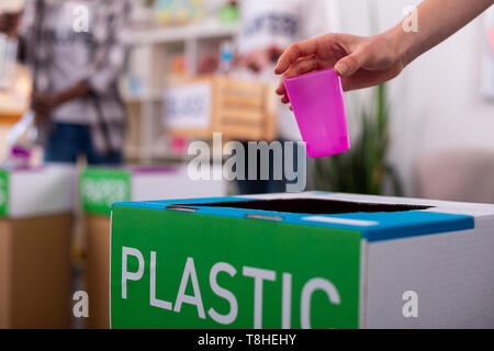 Ragazza mettendo vetro rosa in scatola di plastica con lo smistamento dei rifiuti Foto Stock