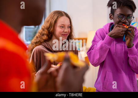 Ragazza ridere mentre avente una piccola pizza party con i migliori amici Foto Stock