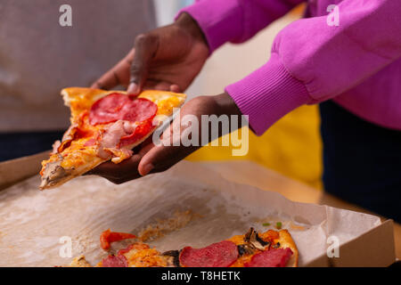 Adolescente in viola felpa tenendo la pizza con salame Foto Stock