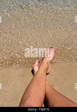 Close-up di una donna di gambe incrociate in corrispondenza della caviglia sulla spiaggia, Malta Foto Stock