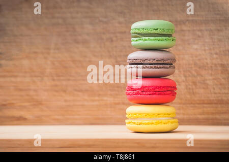 Quattro gustosi colorati macarons francese isolato su texture di legno Foto Stock