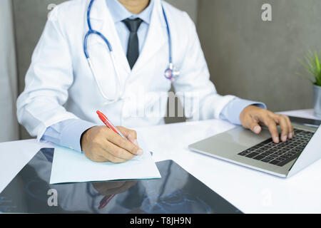 Asian medico lavora al computer in ufficio clinica - Immagine Foto Stock