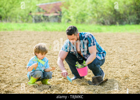 Padre e figlio piantare fiori nel suolo. La giornata della terra. ricco terreno naturale. Eco farm. piccolo bambino aiutare il padre in agricoltura. nuova vita. Mi piace la cura dei fiori. felice giornata della terra. Albero di famiglia. Foto Stock