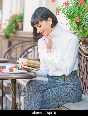 La letteratura per femmina. Ragazza bere il caffè leggere il libro. La tazza di un buon caffè e libro piacevole combinazione migliore per un perfetto fine settimana. La donna bere godono di un buon libro cafe terrazza. Miglioramento di auto concetto. Foto Stock