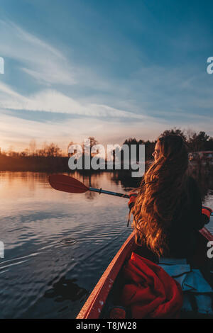 Vista posteriore di felice carina ragazza con pala in un kayak sul fiume Foto Stock