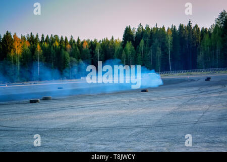 Sfocata immagine di diffusione deriva di gara di auto con un sacco di fumo dalla combustione di pneumatici su pista di velocità. Foto Stock