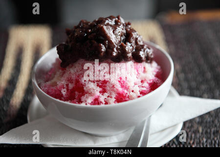 Tradizionale Giapponese del dolce , una ciotola di fagioli rossi dolci con ghiaccio rosso sul modello di legno Foto Stock