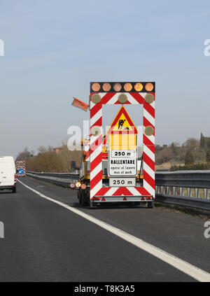 Carrello e lavori stradali in autostrada senza lavoratore e i segni italiana significa che gli uomini al lavoro ridurre la velocità Foto Stock