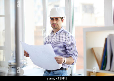 Sorridente ingegnere mediorientale Piani di contenimento Foto Stock
