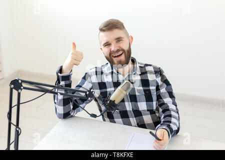 Radio host, streamer e blogger concetto - Ritratto di uomo sorridente gesticolando Thumbs up, che ospita una mostra alla stazione radio o il suo blog Foto Stock