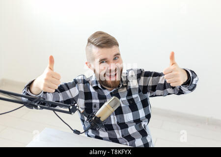 Radio streamer host e blogger concetto - Uomo gesticolando thum fino su sfondo bianco, host alla stazione radio Foto Stock