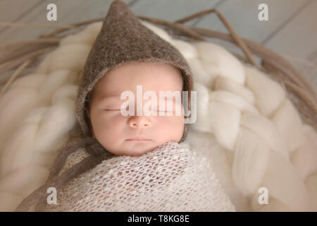 Neonato bambino addormentato indossando un cappello marrone Foto Stock