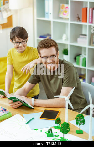 Sorridente uomo interessati in vetri trasparenti che trasportano libro aperto Foto Stock