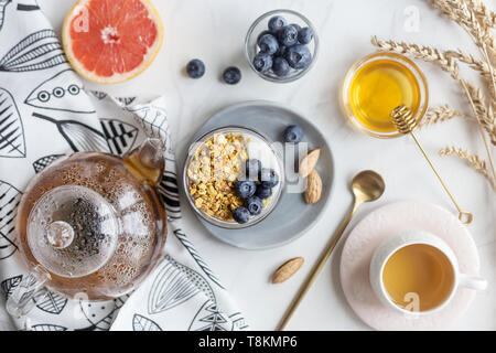 Concetto di una sana prima colazione. Farina di avena con i dadi, frutti di bosco e latte, miele, succo di pompelmo e tè su sfondo bianco con il tovagliolo e cucchiaio. Piatto, laici tabl Foto Stock