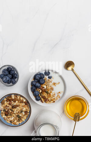 Close up di muesli con yogurt, mirtilli, miele e noci e cucchiaio. Ingredienti per una sana prima colazione Foto Stock