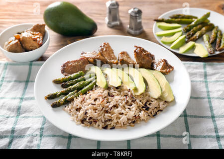 Piastra con riso bollito, verdure e carne sul tavolo Foto Stock