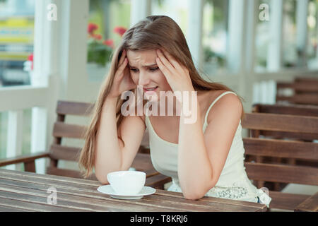 Lo stress. Ritratto sottolineato triste giovane donna con tazza di caffè seduti su una caffetteria alla moda, caffetteria terrazza attorno a piangere. Città urban life style stress. Ne Foto Stock