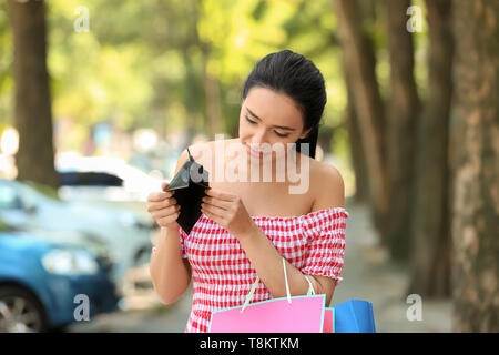 Giovane donna con il portafoglio vuoto dopo lo shopping all'aperto Foto Stock