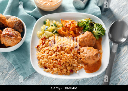 Gustoso riso bollito con polpette di carne e verdure sulla piastra Foto Stock