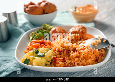 Gustoso riso bollito con polpette di carne e verdure sulla piastra Foto Stock