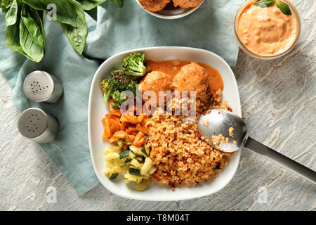 Gustoso riso bollito con polpette di carne e verdure sulla piastra Foto Stock