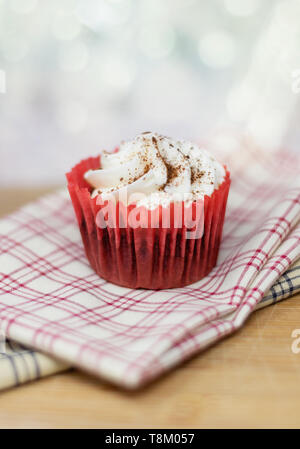 Red Velvet cupcake decorativo su plaid tessuto con una profondità di campo ridotta e un sfondo bokeh di fondo Foto Stock