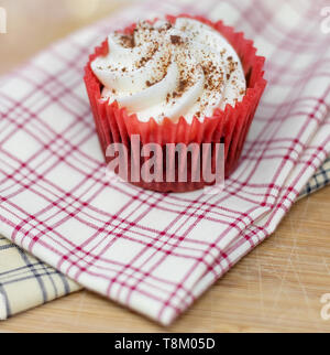 Red Velvet cupcake decorativo su plaid tessuto con una profondità di campo ridotta Foto Stock