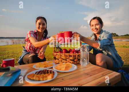 Un gruppo di amici asiatici a bere caffè e passare il tempo facendo un pic-nic in estate vacanze.sono felici e divertirsi in vacanza. Foto Stock