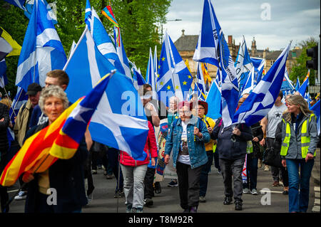 Si vedono persone marciando con bandiere durante la protesta. Migliaia di indipendenza scozzese sostenitori hanno marciato attraverso Glasgow come parte del "tutto sotto uno striscione' (AUOB) protesta, come la coalizione si propone di eseguire tale evento fino a che la Scozia è 'libero'. Foto Stock