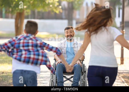 Giovane uomo in carrozzella a giocare con la sua famiglia all'aperto Foto Stock