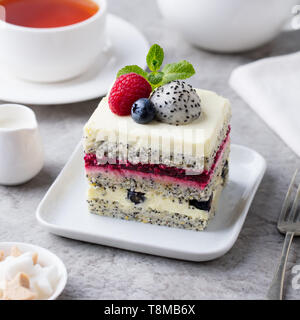 Berry, semi di papavero torta a strati sulla piastra bianca. Sfondo grigio. Foto Stock