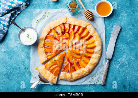 Peach galette, torta, torta con crema su sfondo blu. Vista dall'alto. Foto Stock