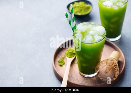 Matcha ice tea nel bicchiere alto sul piatto di legno. Grigio pietra dello sfondo. Copia dello spazio. Foto Stock